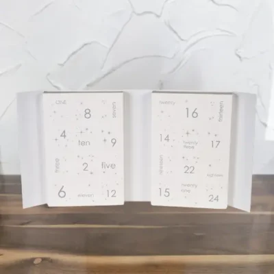 Open view of Kakes & Kanvas' Large Holiday Advent Calendar, showcasing individual compartments with numbers in a unique font on a white background