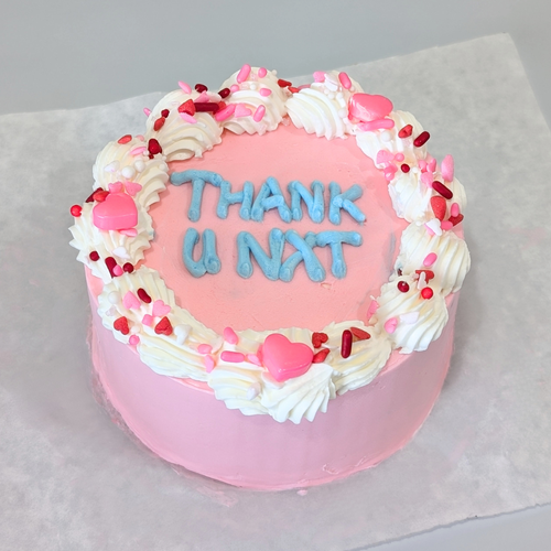 A pink Naughty Bento Cake with playful buttercream piping, heart decorations, and a cheeky message, perfect for a fun and lighthearted Valentine’s treat.